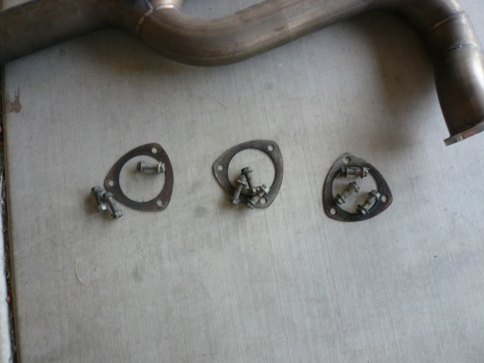 Exhaust pipe with three triangular gaskets and bolts on concrete
