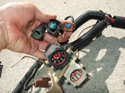 1992 Ford Probe - A hand holds several electrical connectors from a vehicle wiring harness.