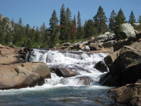 1999 Jeep Grand Cherokee - A scenic view of a waterfall cascading over rocks in a natural environment under a clear blue sky.