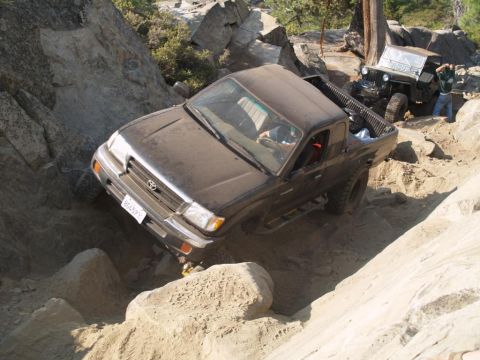 1999 Jeep Grand Cherokee - Two off-road vehicles, a Toyota Tacoma and a Jeep, tackle a challenging rocky terrain.