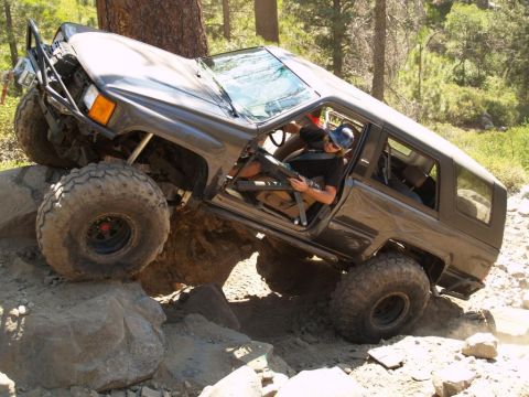 1999 Jeep Grand Cherokee - An off-road SUV navigates a challenging rocky terrain on a sunny day.