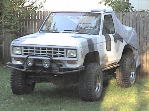 1987 Ford Bronco II - This Ford Bronco II has a camouflage paint job and a tarp covering its rear section.