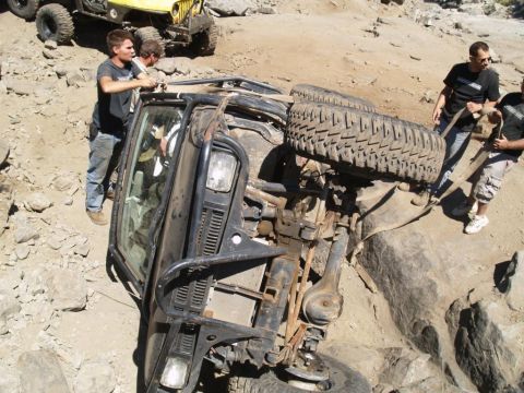 1999 Jeep Grand Cherokee - Men attempt to right an overturned Jeep Wrangler on a rocky trail; another Jeep is in the background.