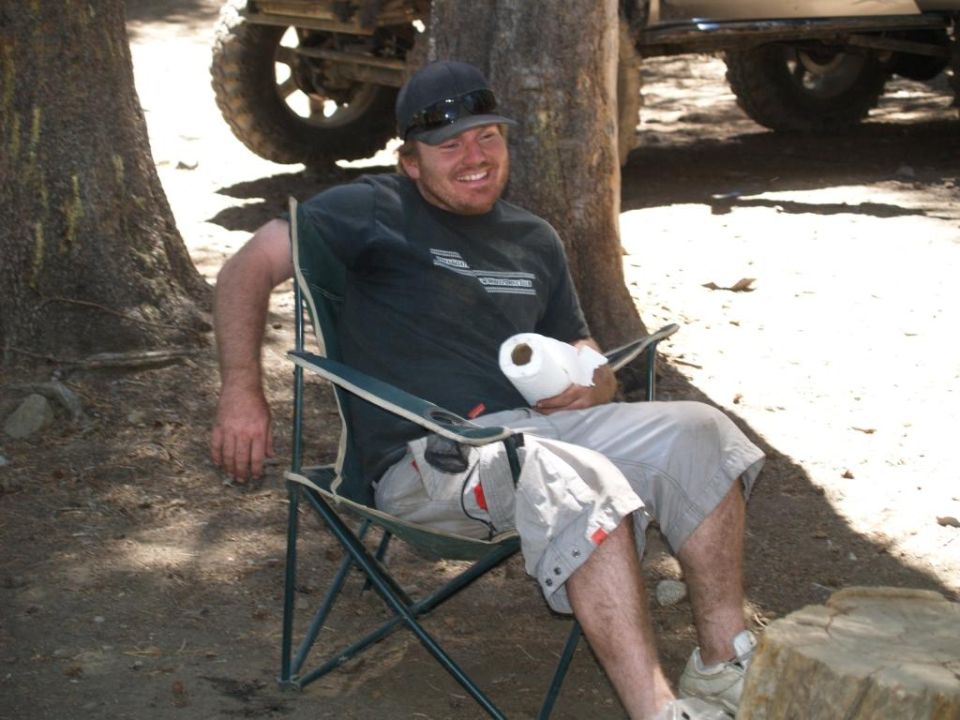 Man in camping chair holding toilet paper