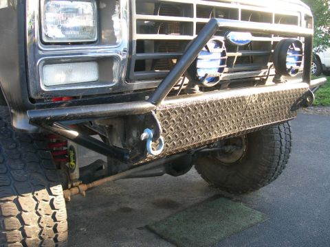 1985 Ford Bronco - Close-up of a Ford Bronco's front end, a custom bumper and auxiliary lights.