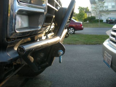 1985 Ford Bronco - Close-up of a black Ford Bronco's front end, showing the bumper and grille, with other vehicles in the background.