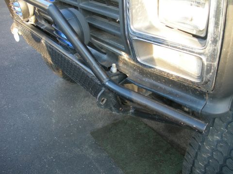 1985 Ford Bronco - Close-up view of the front bumper and headlight assembly of a vehicle from the 1980s, an aftermarket brush guard.