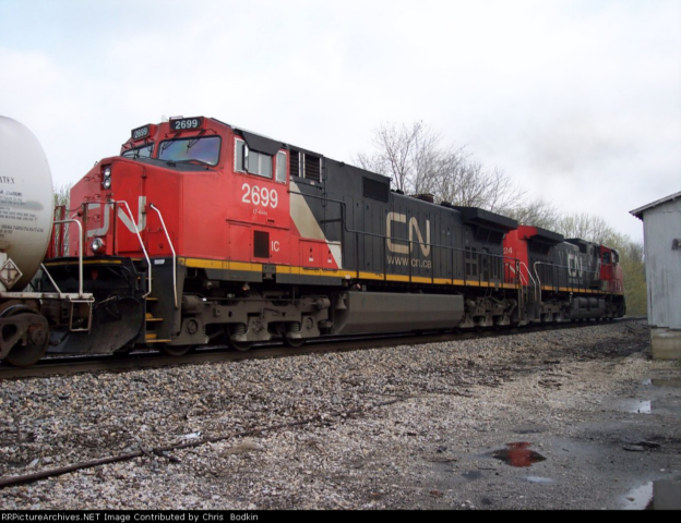 CN train locomotive 2699 with another locomotive behind it, parked on tracks next to a building