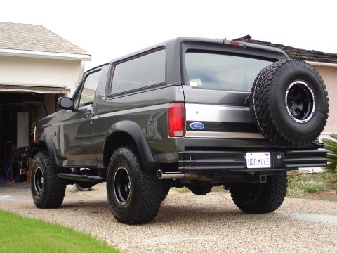 1994 Ford Bronco - This Ford Bronco is parked in front of a garage with a spare tire mounted on the rear tailgate.