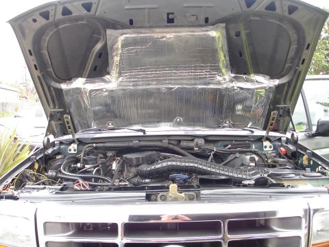 1994 Ford Bronco - Engine bay of a 1994 Ford Bronco with the hood open, revealing the engine and insulation on the underside of the hood.