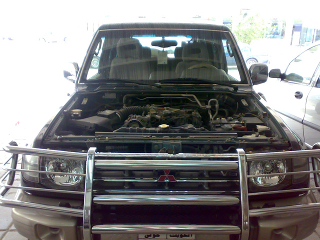 Front view of a Mitsubishi Pajero with the hood open, showing the engine bay. It has a chrome bull bar