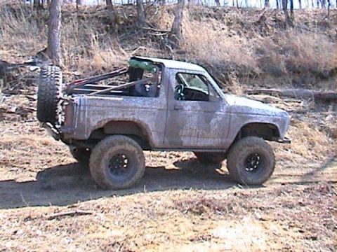 1987 Ford Bronco II - A dirty 1987 Ford Bronco II is shown from a three-quarter front angle on an outdoor trail.