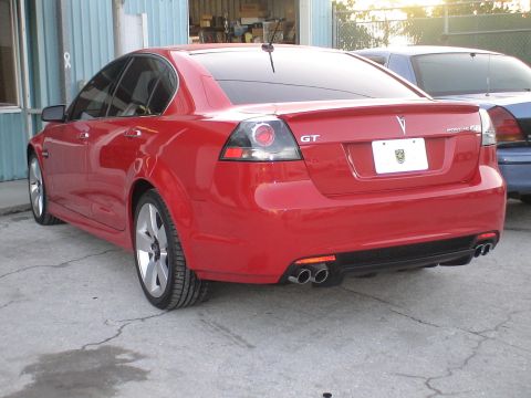 1993 Ford C-350 (Centurion Conversions) - Red Pontiac G8 GT sedan with dual exhaust and spoiler parked outdoors.