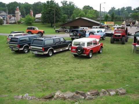 1995 Ford C-150 (Centurion Conversions) - Several vehicles are parked on a grassy field during an outdoor event.