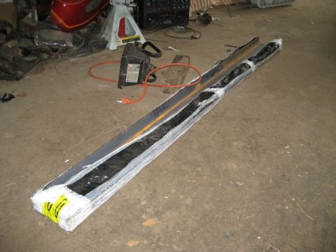 1995 Ford Bronco - Wrapped automotive part on floor, possibly a bumper or trim piece.
