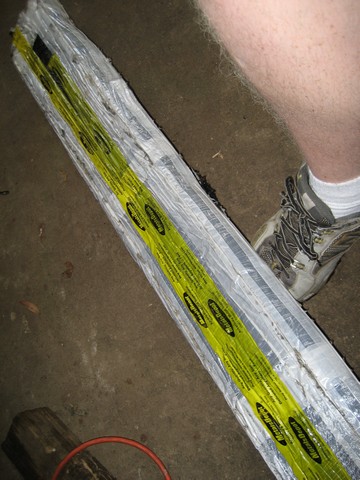 1995 Ford Bronco - A person's leg and shoe are visible next to a wrapped bumper with yellow labeling.