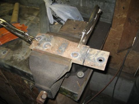 1995 Ford Bronco - A rusted metal bracket is secured in a vise, ready for work.