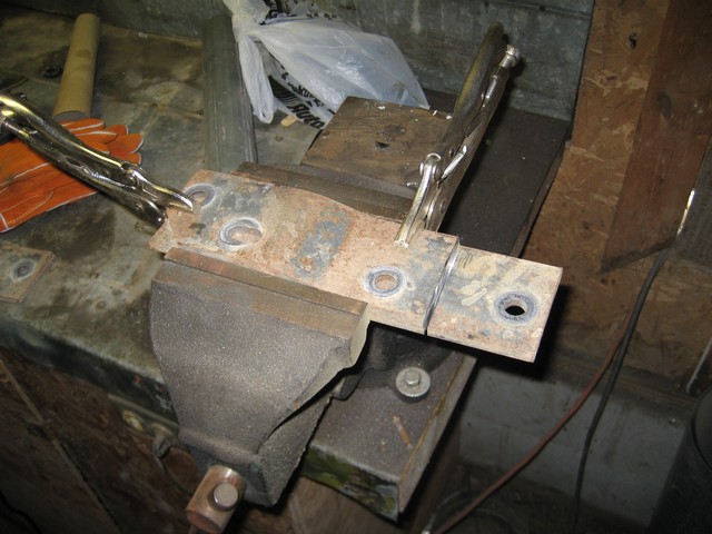 Rusted metal bracket clamped in a vise with locking pliers