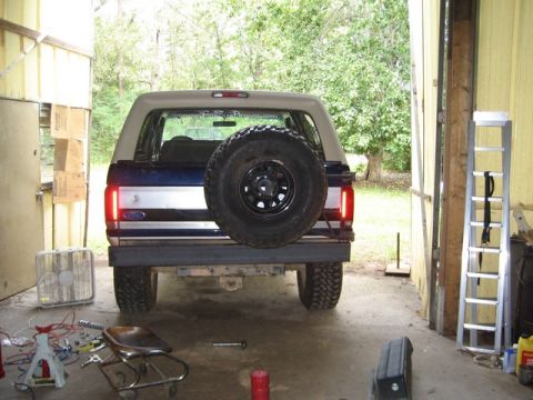 1995 Ford Bronco - Rear view of a 1995 Ford Bronco parked inside a garage, showing the spare tire and taillights.