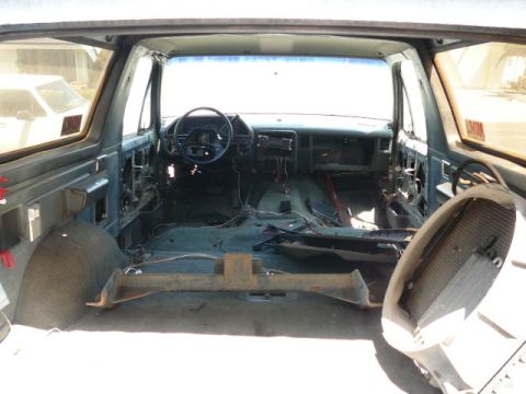 1988 Ford Bronco - Gutted interior of a full-size SUV shot from the open rear hatch looking forward, with all seats, carpet and console removed to expose the…