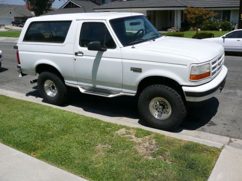 1988 Ford Bronco - White two-door Ford Bronco full-size SUV with removable hardtop, photographed in 3/4 front view from the passenger side while parked at a s…