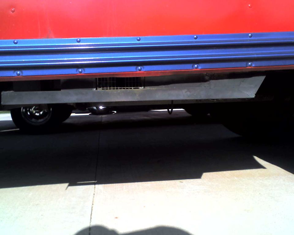 Red and blue school bus side view, showing undercarriage with a metal grate and wheel