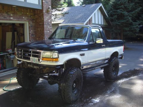 1993 Ford Bronco - This lifted Ford Bronco has a two-tone paint scheme and is parked in a driveway.
