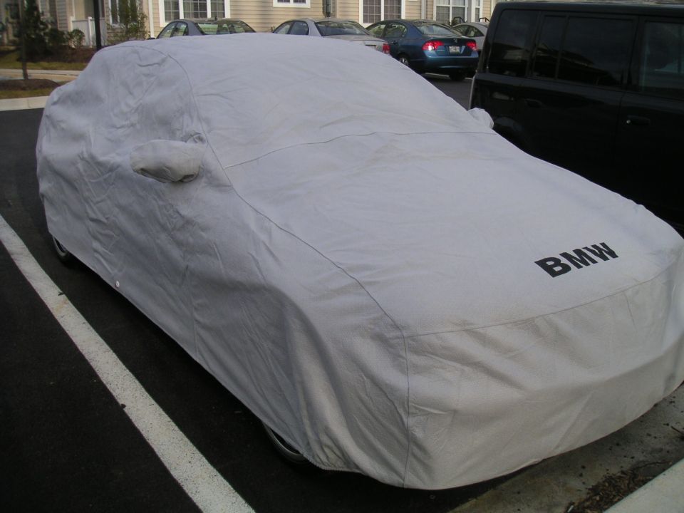 Car covered with a gray BMW car cover parked in a lot