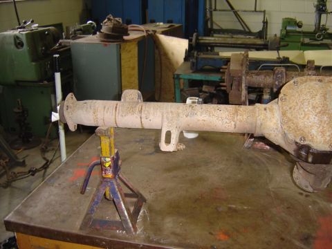 1996 Ford Bronco - A rear axle assembly is supported by jack stands on a workbench in a cluttered garage or workshop.