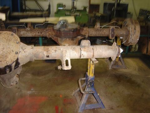 1996 Ford Bronco - A rusty rear axle assembly, likely from an older vehicle, is supported by jack stands in a workshop setting.