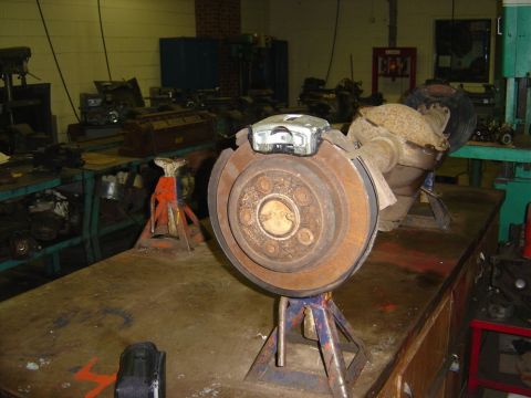 1996 Ford Bronco - Rear axle assembly with brake rotor and caliper displayed on jack stands in a workshop.