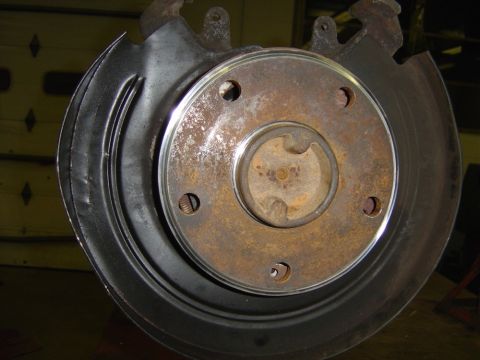 1996 Ford Bronco - Close-up view of a vehicle's rear disc brake assembly, showing a rusty rotor and a black dust shield.