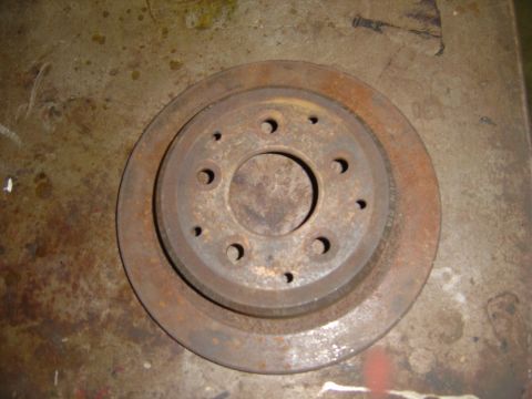 1996 Ford Bronco - A single rusty brake rotor is shown against a concrete background.