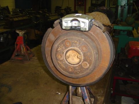 1996 Ford Bronco - A rusty rear disc brake assembly is shown mounted on jack stands in a workshop.