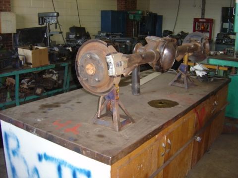 1996 Ford Bronco - A rear axle assembly disc brakes is displayed on jack stands in a workshop setting.