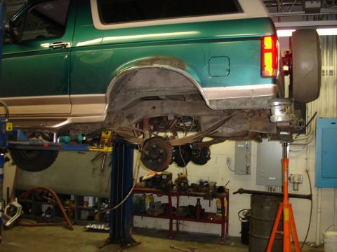 1996 Ford Bronco - Rear view of a green SUV on a lift, highlighting its suspension system and leaf springs.