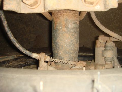 1996 Ford Bronco - Close-up view of a vehicle's rear disc brake assembly, showing the brake line and a tension spring.