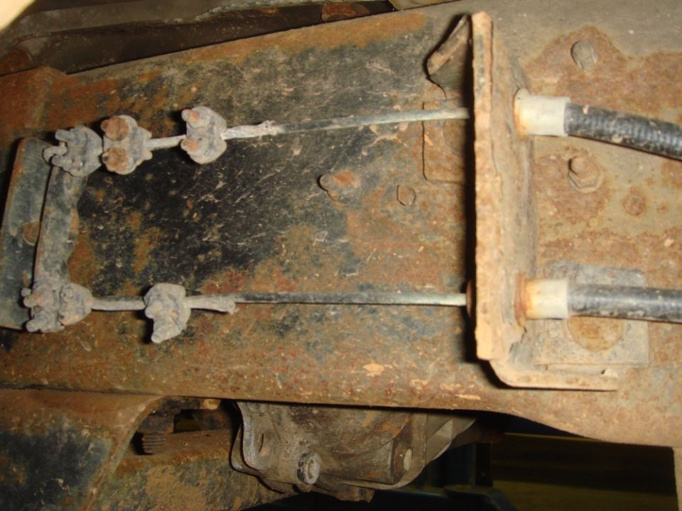 Close-up of rusted metal frame with two brake cables attached to brackets