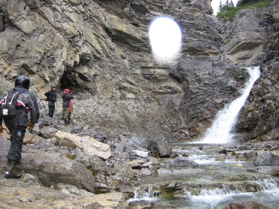 People standing by a waterfall in a rocky canyon.