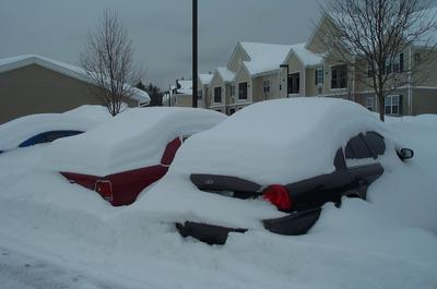 1991 Ford Crown Victoria LTD - Cars are completely buried under a thick blanket of snow after a winter storm.