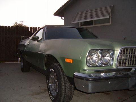 1973 Ford Ranchero - A light green 1973 Ford Ranchero is parked in a driveway next to a house. The front passenger side of the vehicle is visible, showing the h…