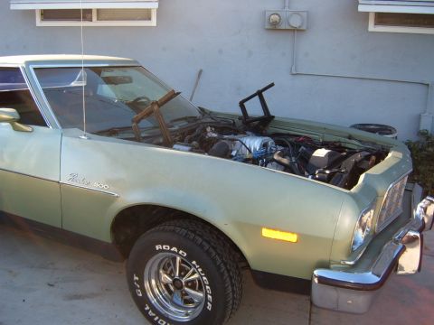 1973 Ford Ranchero - A light green 1973 Ford Ranchero is parked outside with its hood open, revealing the engine. The vehicle has chrome trim and a "Ranchero 50…