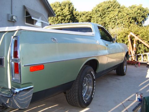 1973 Ford Ranchero - The rear passenger side of a light green 1973 Ford Ranchero is shown parked on a concrete surface. A chrome bumper and a red reflector are…