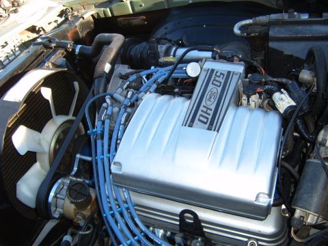 1973 Ford Ranchero - Close-up view of an engine bay, showing a metal cover and blue hoses.