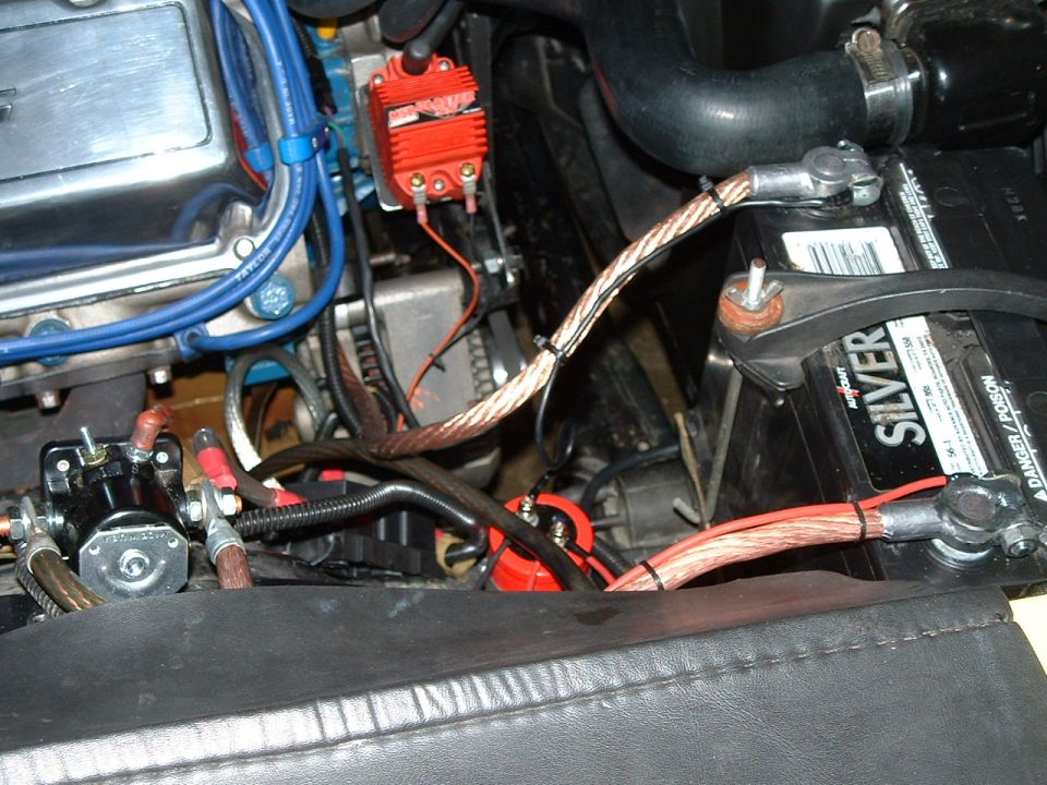 Close-up of car battery and engine wiring, including a red ignition module