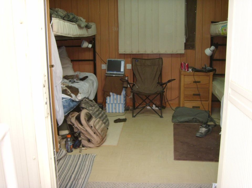 Interior of a small cabin with bunk beds, a camp chair and gear