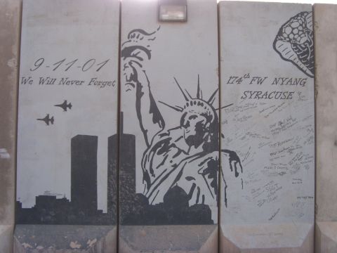1978 Ford Bronco - Mural painted across concrete T-wall barriers reading "9-11-01 We Will Never Forget" with the Twin Towers skyline, two fighter jets, a larg…