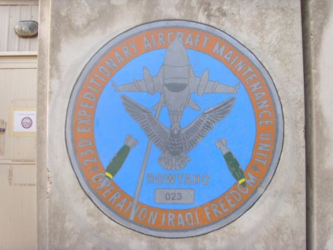 1978 Ford Bronco - A painted unit emblem on a weathered concrete wall reading "23D Expeditionary Aircraft Maintenance Unit, Operation Iraqi Freedom," with a f…
