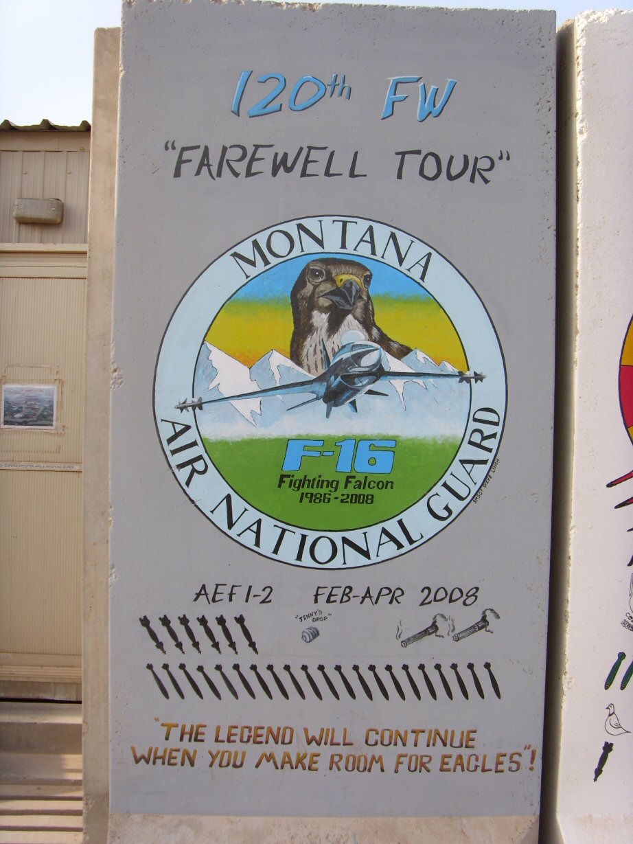 Mural on concrete barrier with F-16 fighter jet and falcon emblem