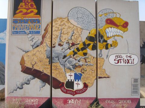 1978 Ford Bronco - A military deployment mural painted across three concrete blast barriers, showing a snarling cartoon hornet holding wrenches over a cracked…